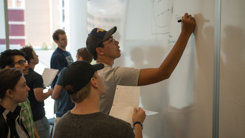 Economics students solving problems on the board