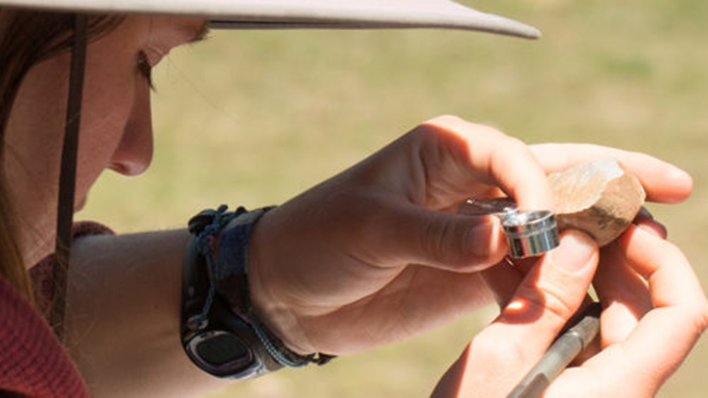 person examining a rock in the field