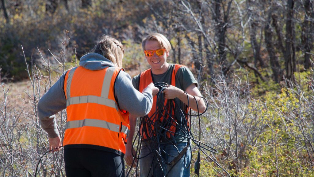 Two students working with wire during their geophysics field session