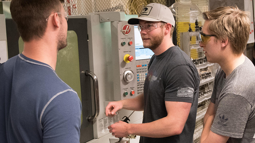 students working with machinery in the machine lab