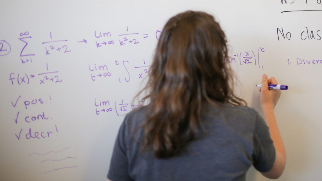 Student doing math problems on a whiteboard