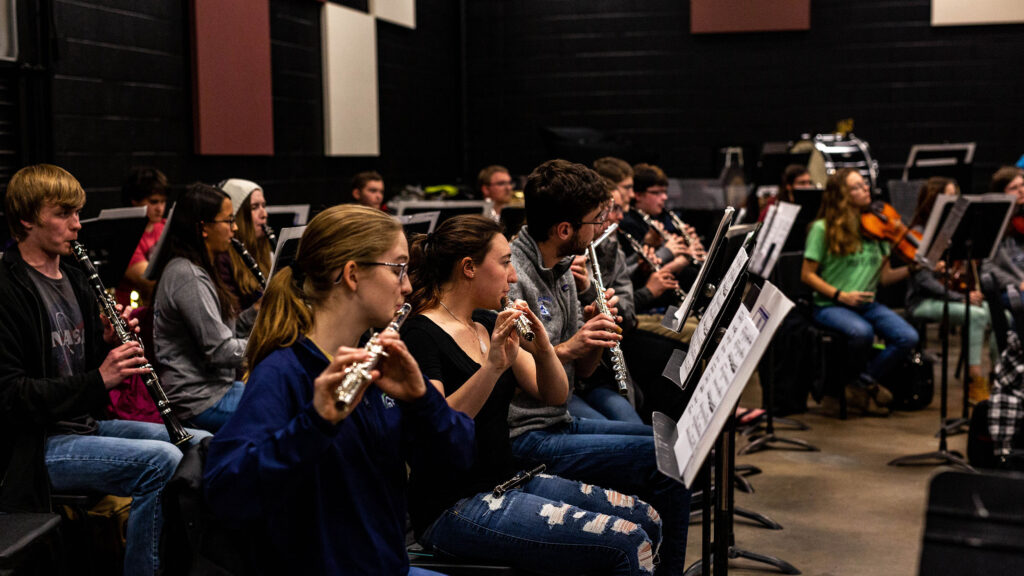 Students in orchestra playing their instruments during the concert.