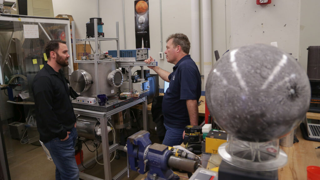 Adults standing around in a lab with large machines around them