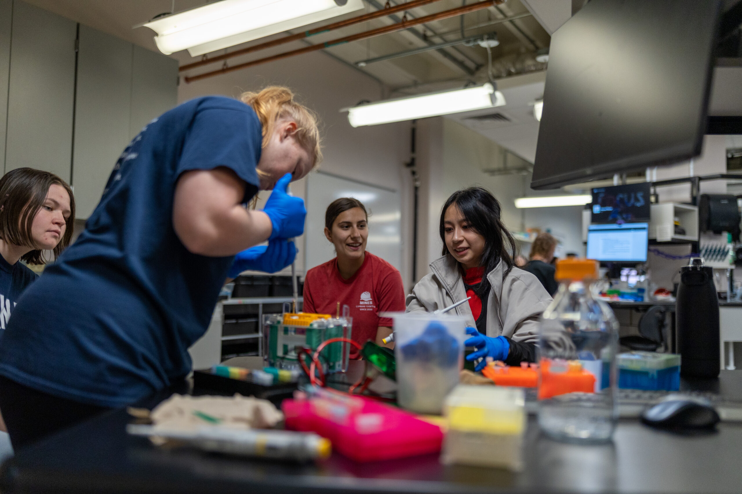 QBE Field Study QBE students collaborating on a project in a laboratory setting with various instruments and equipment