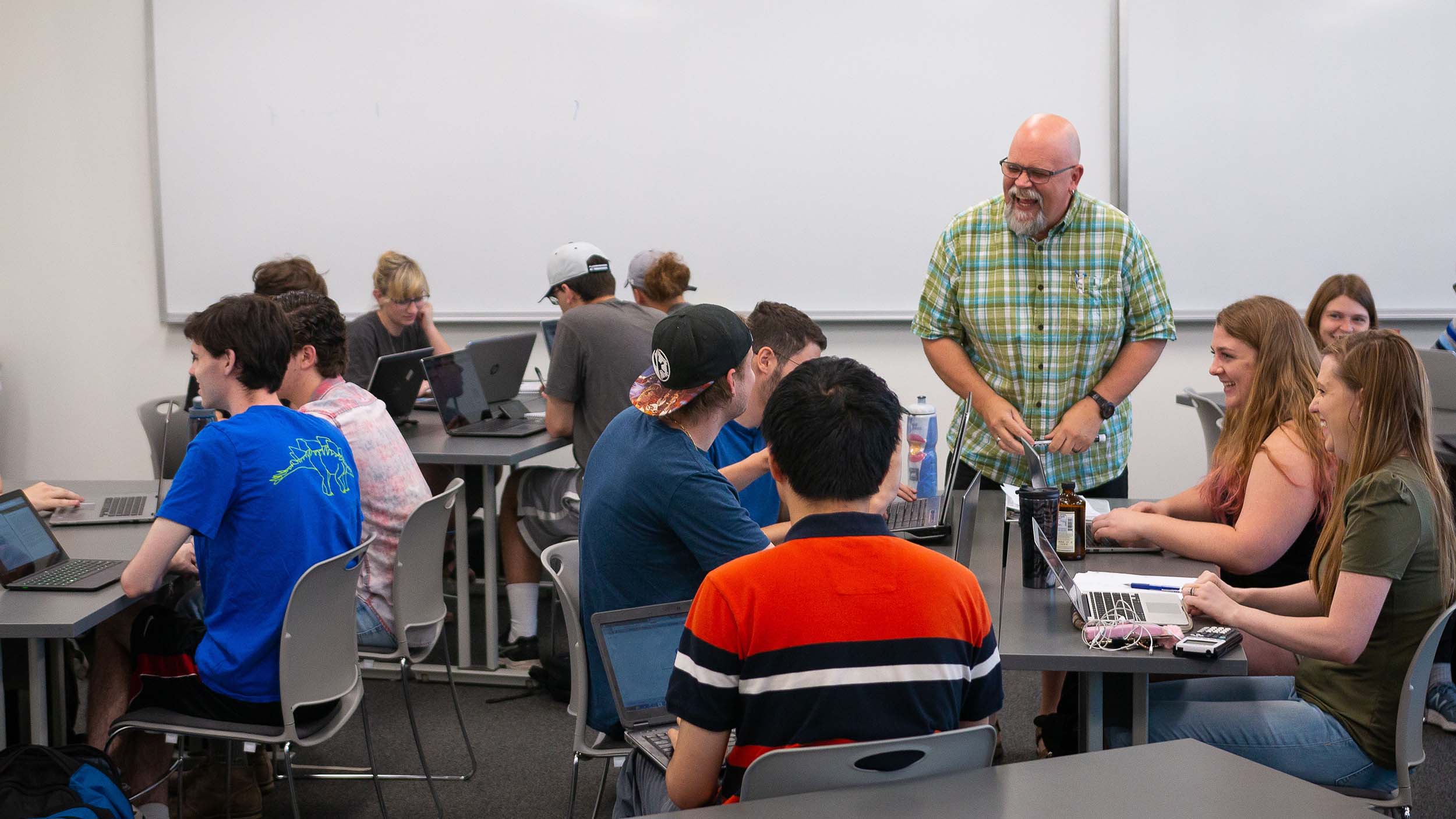 Professor laughing with students in a classroom