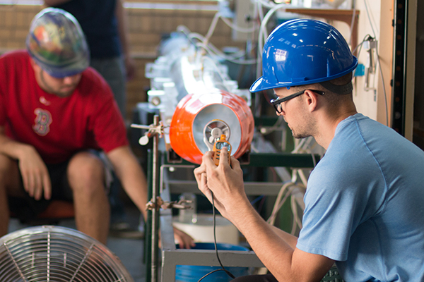 2 students in hardhats working in shop