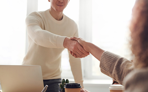 man and woman shaking hands over desk