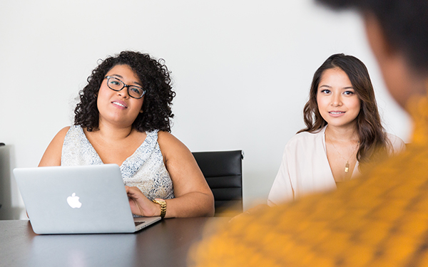 two women at a table with laptop in front of one fo them