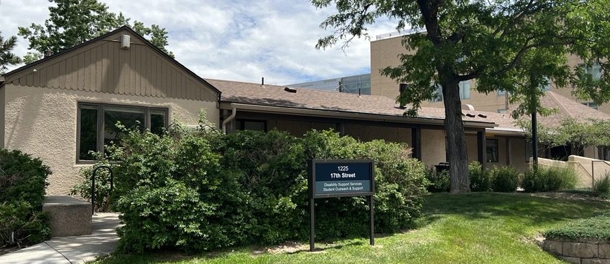 A tan, one-story building with a brown roof and surrounded by large shrubs and several trees in the front. There's a sign in front of the shrubs that says 1225 17th Street; Student Disability Services, Student Outreach and Support.