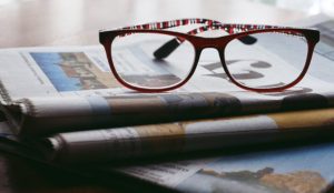 stack of newspapers with red glasses on top of stack