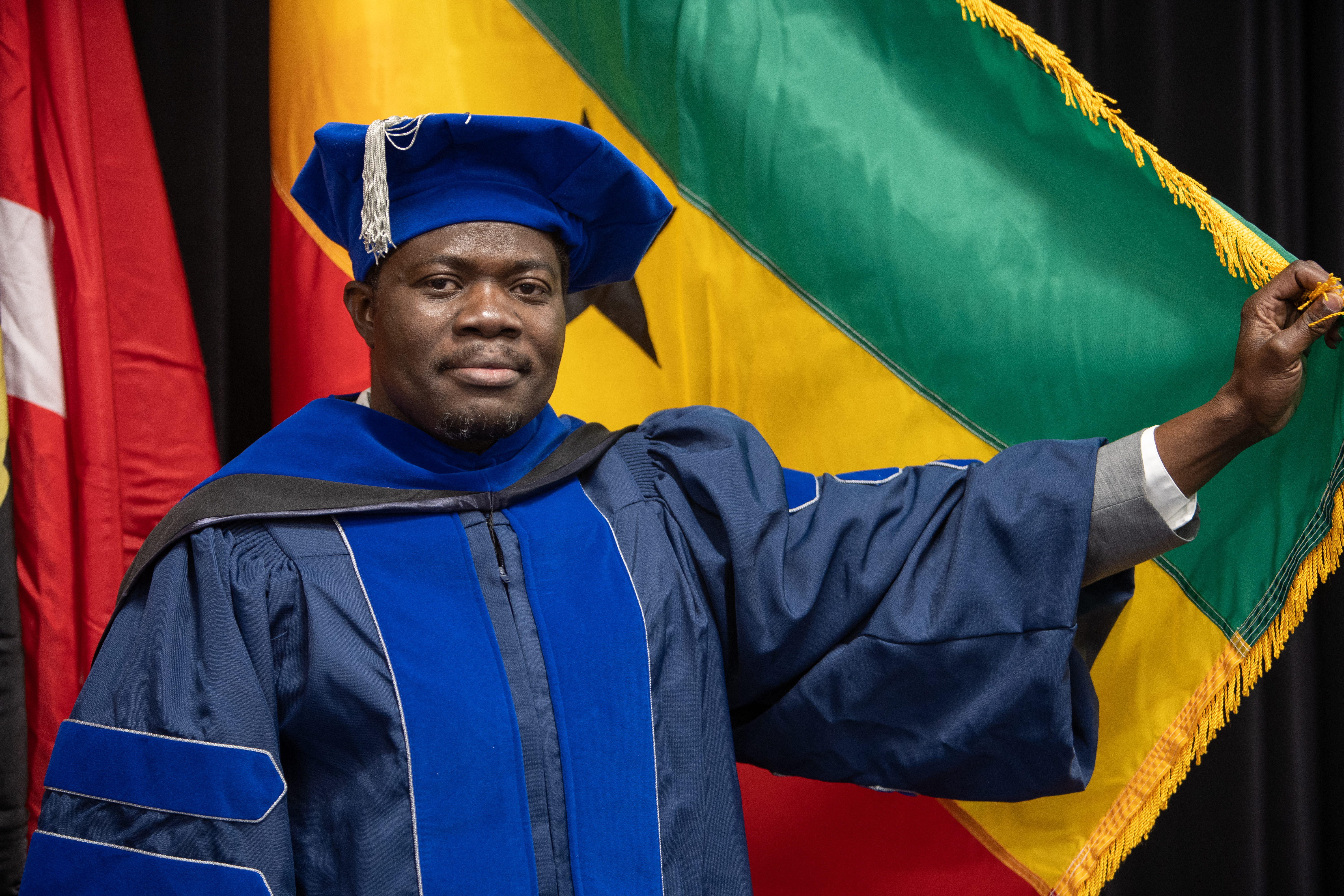 graduate student at commencement holding national flag