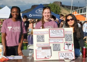 Three students show off their informational poster board about AMWA