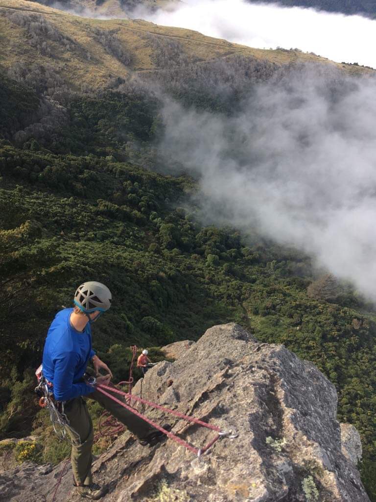 Photo Credit: Banks Irelan 2020 Two people repelling off a mountain side with clouds and green trees beneath them