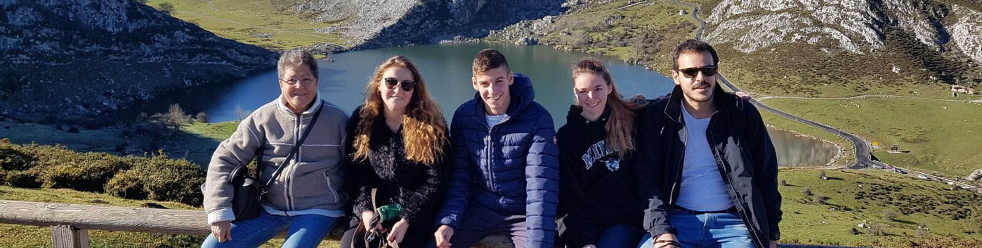 Group of five posing in front of a mountain valley with small lake below