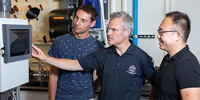 three professors looking at lab equipment