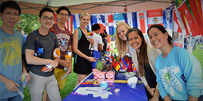 group of students surrounded by international flags, smiling at camera