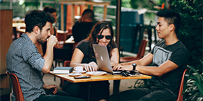 three students sitting at table and drinking coffee