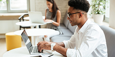 student in bright room at table on laptop