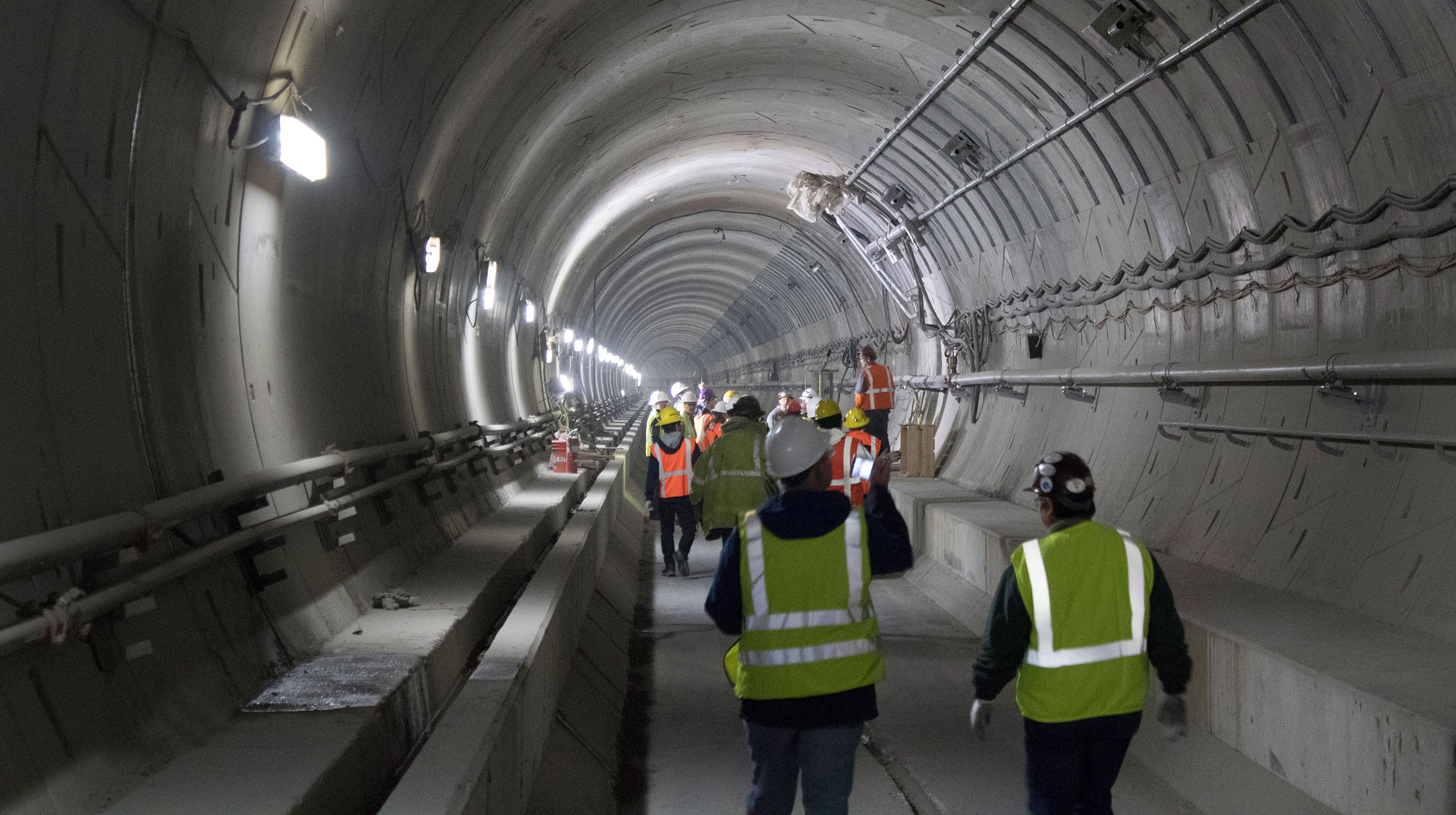 A group of construction workers walking through a tunnel.