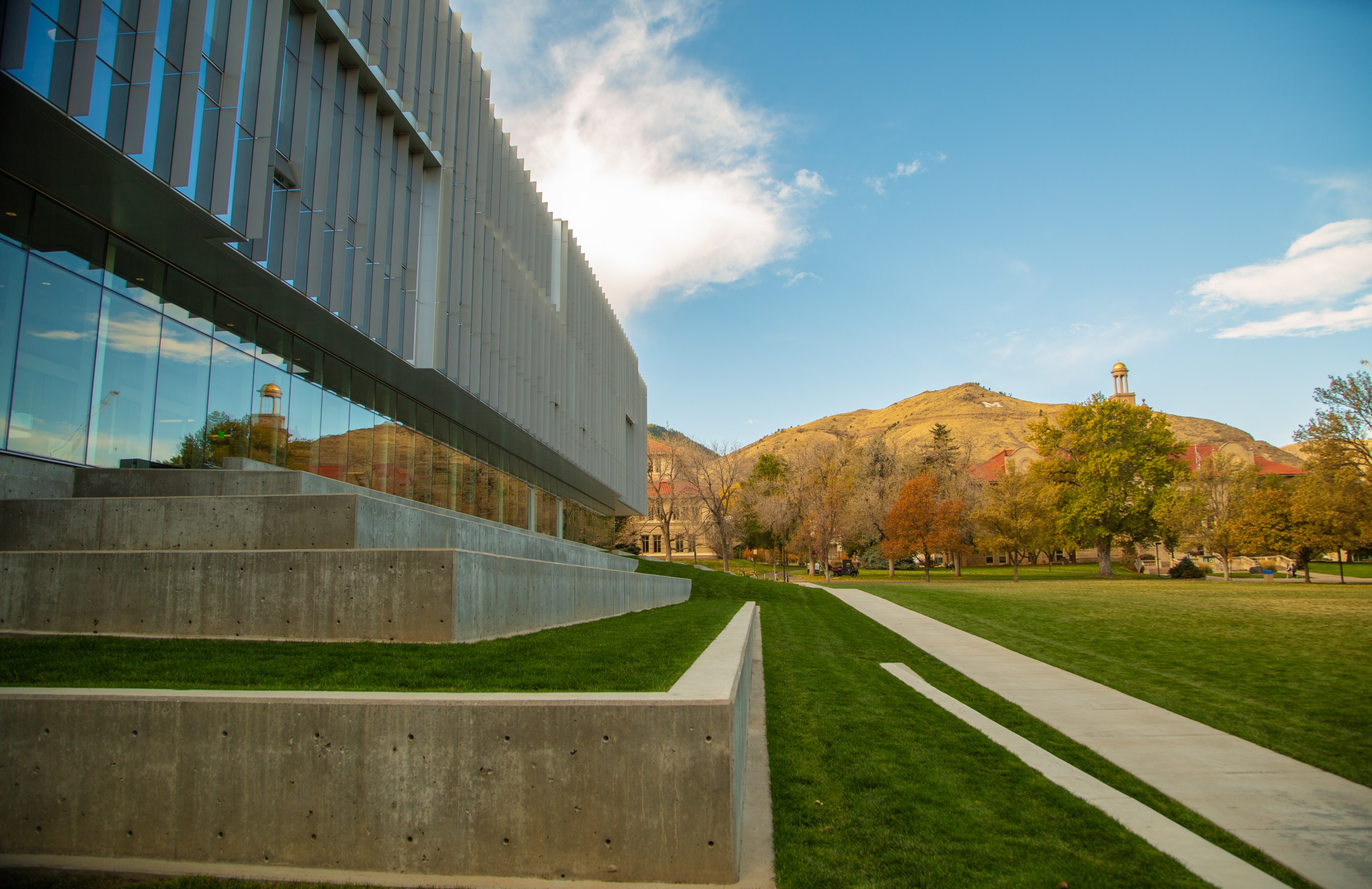 View from CoorsTek Center's steps across a fall campus lawn toward Guggenheim Hall's tower and the "M" on Mount Zion.