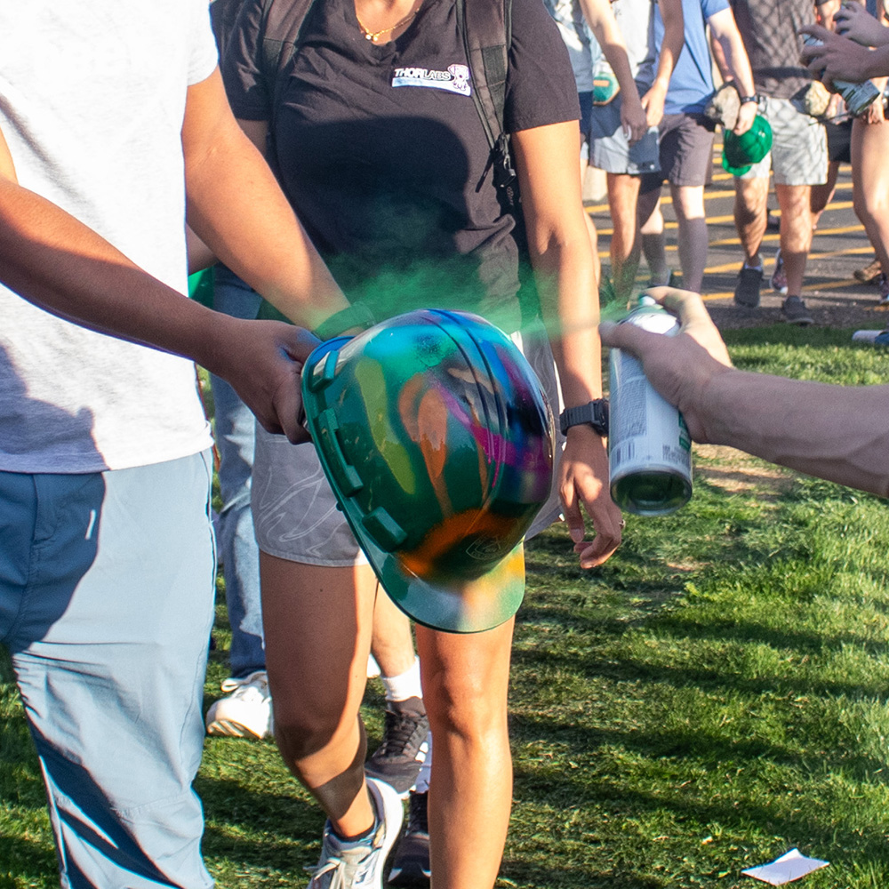 Student holding out their hard hat before climbing up to the M to get their hat spray painted. 