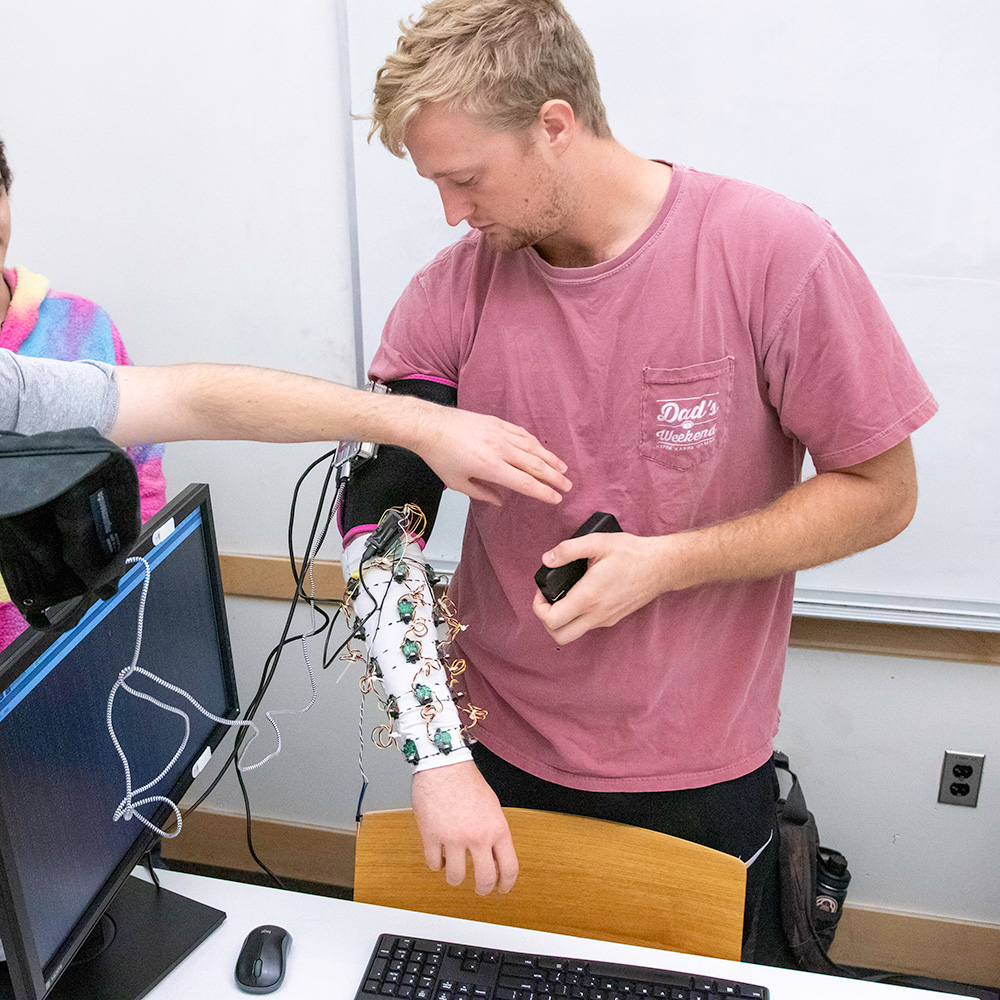 Student trying on their prosthetic arm that they created during their capstone project