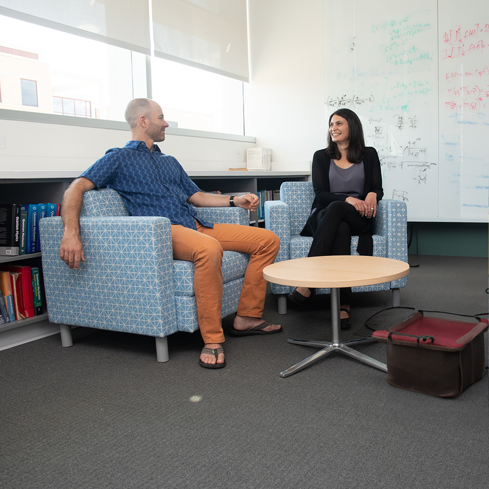 Two professors sitting together and in conversation.