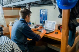 student typing on laptop in dorm room