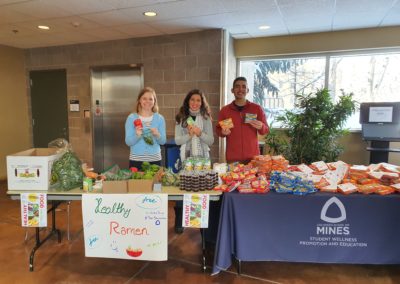 Students standing behind a table holding samples of health raman