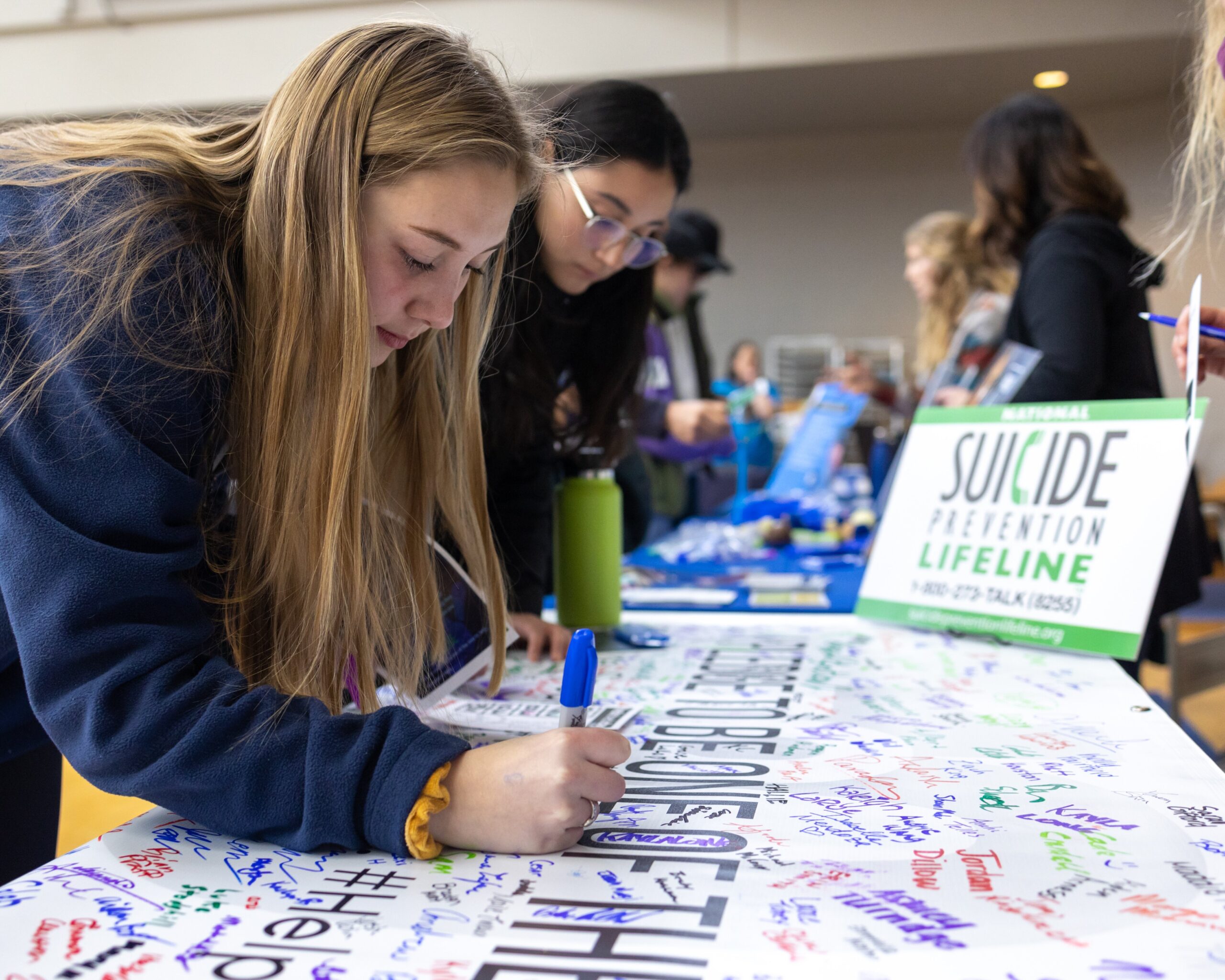 Student signs the Nine out of Ten pledge to be aware, speak up, reach out and help someone.