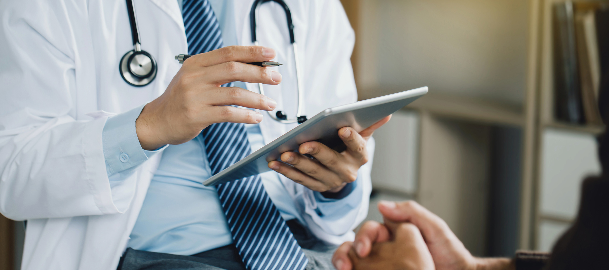 A doctor analyzing information on his tablet with the patient