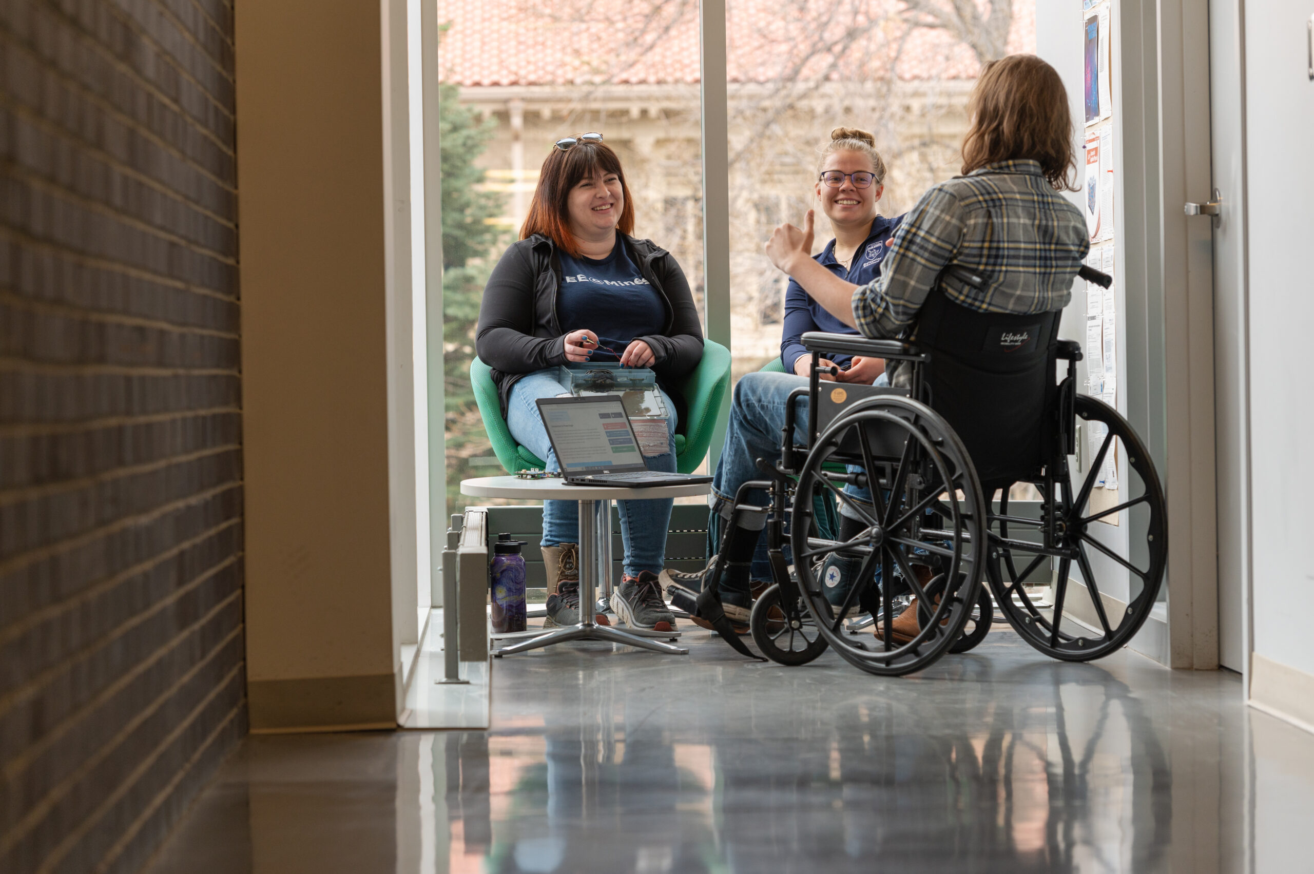 Three students talking in a hallway.
