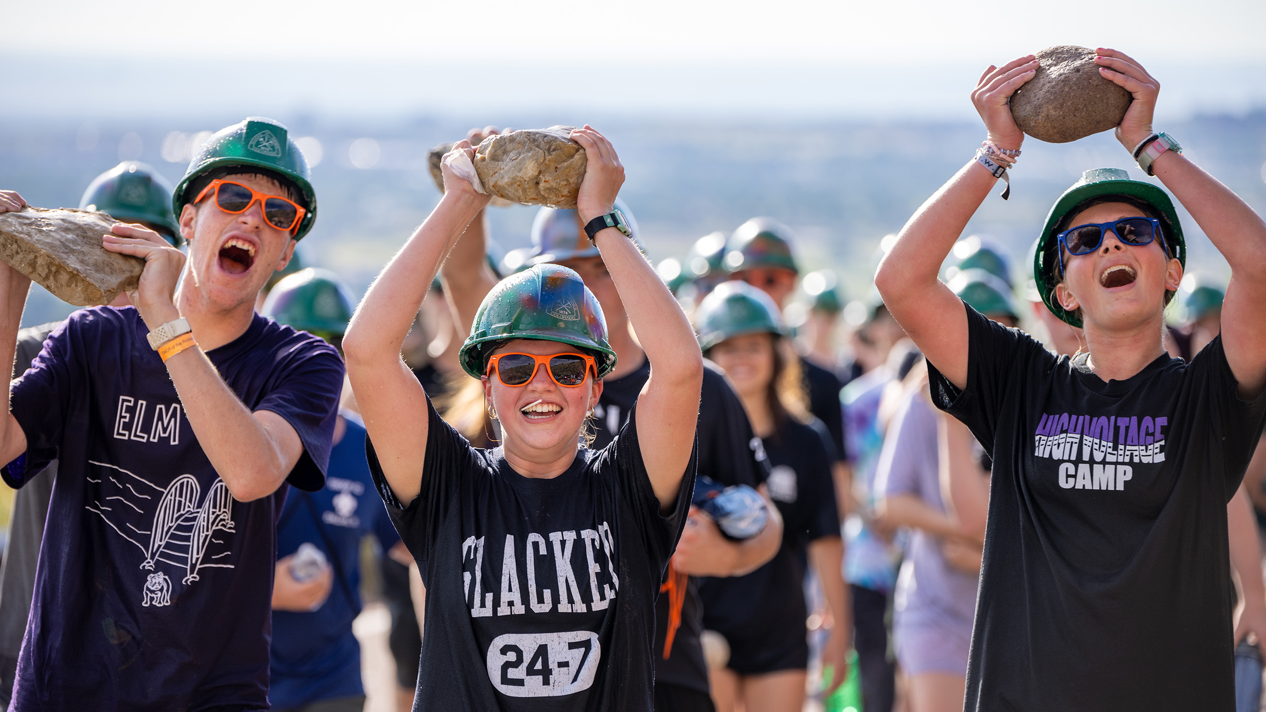 Mines students holding rocks over their heads at the M Climb