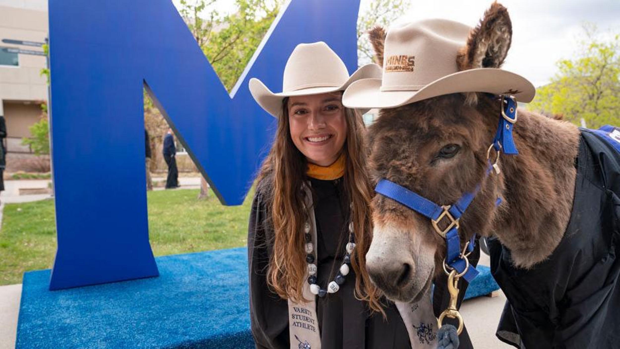 Blaster the Burro posing for a photo with a Mines student at Commencement Ceremonies