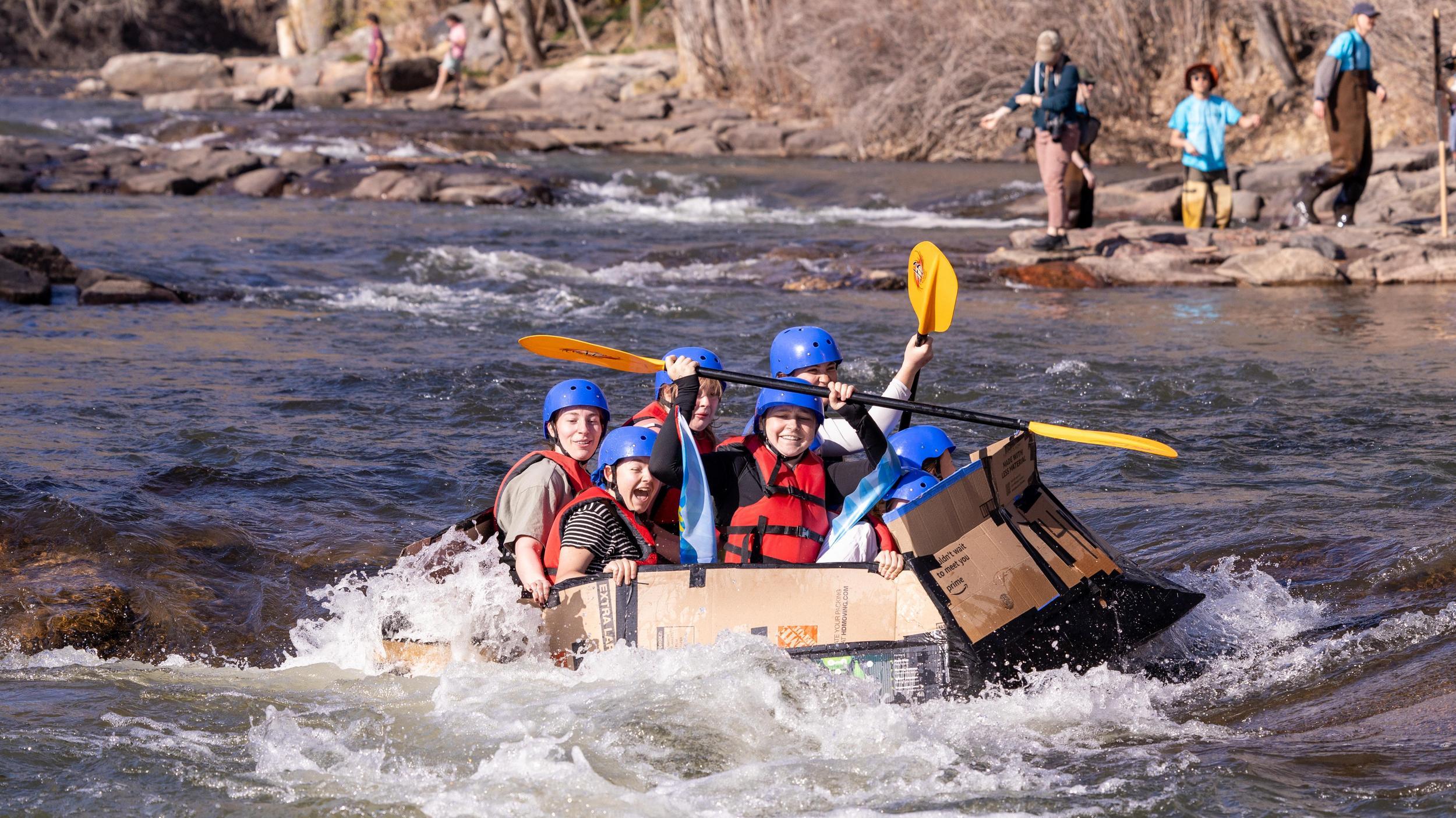 Students riding over a rapid in a cardboard boat during the 2025 E-Days