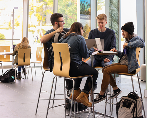 four students studying at tall table in atrium