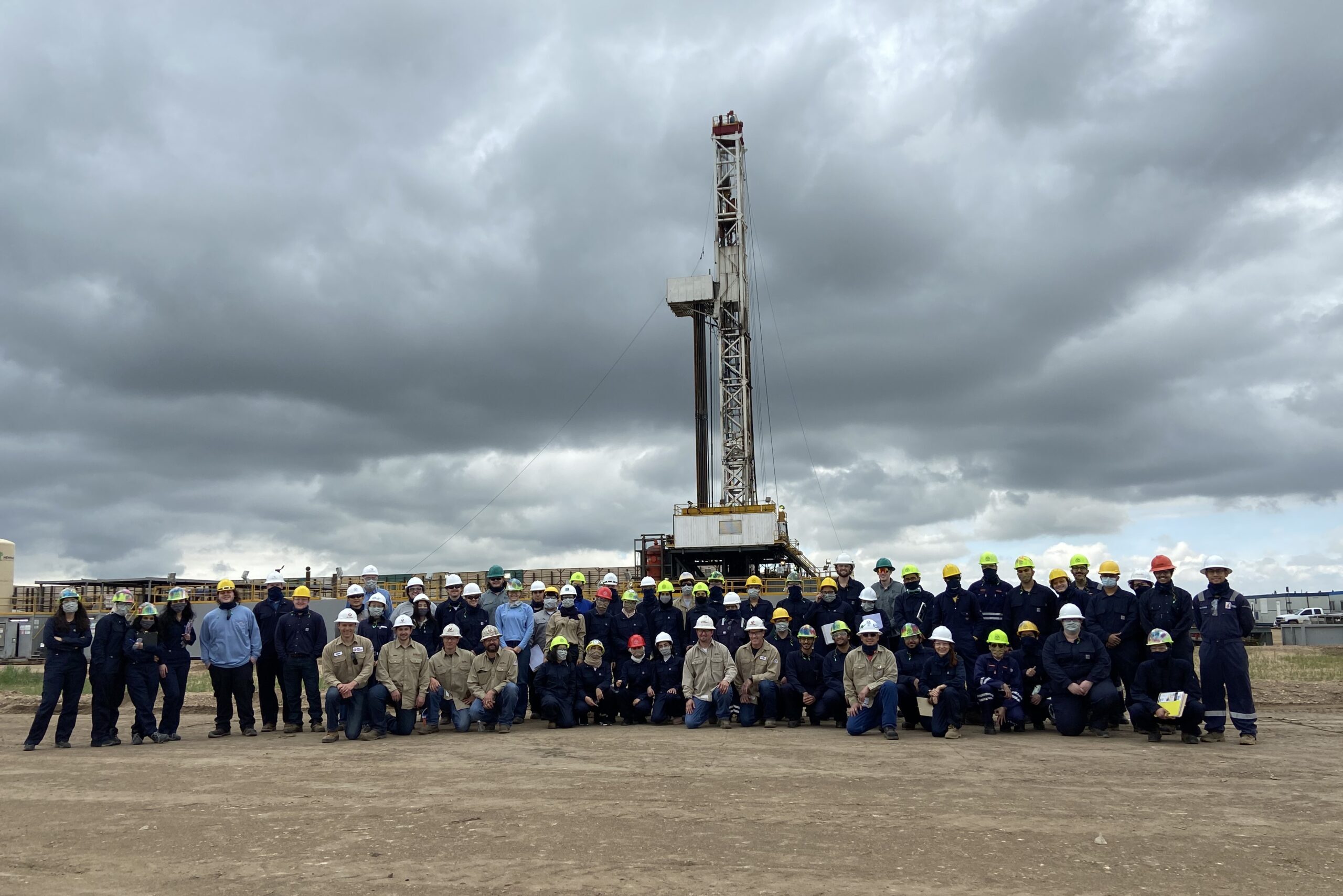 A group of students in front of a oil derrick.