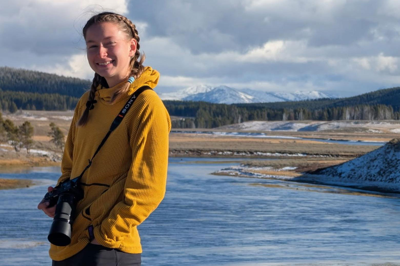 Anna Williams, Mines Geophysics student, posing in front of a body of water and mountain scenery